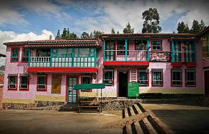 um edifício cor-de-rosa com uma placa à frente. em Hotel Los Geranios em Duitama