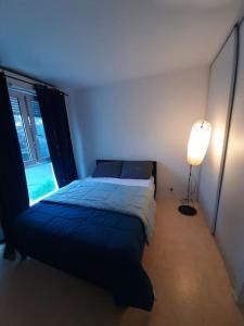 a bedroom with a bed and a lamp and a window at Logement T2 tres propre in Cergy +1 photo