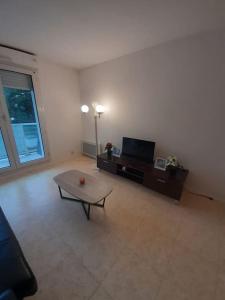 a living room with a table and a tv at Logement T2 tres propre in Cergy