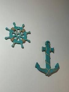 a green metal anchor on a white background at Casa toda Equipada 900 metros da Lagoa, próxima as praias in São Pedro da Aldeia