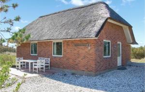 a small brick building with a table and chairs at Holiday Home Fyrmarken Hvide Sande Iv in Nørre Lyngvig