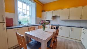 a kitchen with a wooden table with a vase of flowers on it at Spacious Victorian Apartment in Edinburgh City in Edinburgh