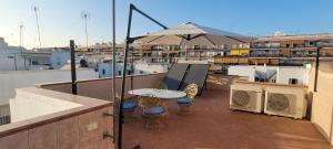 a balcony with a table and an umbrella on a roof at Casa El limonero in Seville