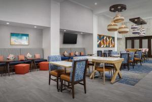 a dining room with tables and chairs and a tv at Hampton Inn & Suites Naples South in Naples