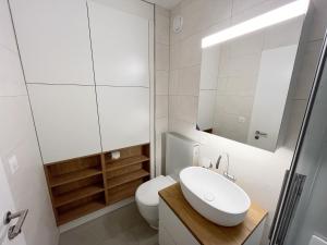 a white bathroom with a sink and a toilet at Bel Appartement Centre Crans Montana, Vue Alpine et Fraîcheur in Crans-Montana