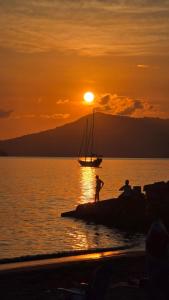 two people standing on the beach at sunset with a sail boat at Chambre Bachacha in Dzaoudzi