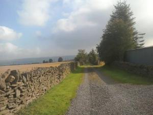 eine Steinmauer neben einer unbefestigten Straße in der Unterkunft Quarry Cottage in Consett