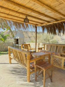 una mesa y sillas bajo una sombrilla de madera en Panorama garden inn, en Máncora