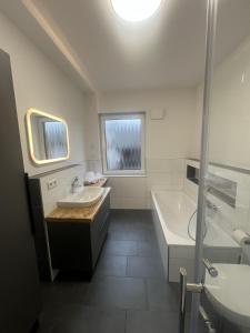ein Badezimmer mit einer Badewanne, einem Waschbecken und einer Badewanne in der Unterkunft Schöne Ferienwohnung in Buxtehude- Zentral -Lade Säule -6Person in Buxtehude + 1 Foto