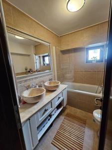 ein Badezimmer mit zwei Waschbecken, einem Spiegel und einer Badewanne in der Unterkunft City Hall Apartament in Craiova