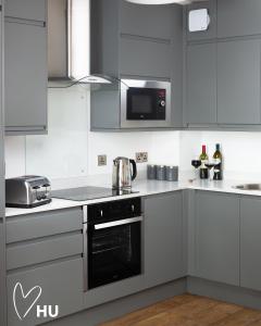 une cuisine avec des armoires blanches et un four à plaques de cuisson dans l'établissement Boutique 1 Bdrm Duplex Suite on Marina-105, à Hull 2 autres photos