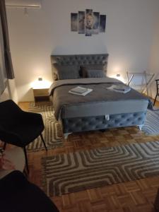 a bedroom with a bed and a chair and a rug at Studio apartman Valentina in Vukovar