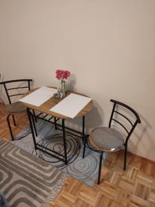 a table with two chairs and a table with flowers on it at Studio apartman Valentina in Vukovar
