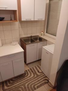 a kitchen with white cabinets and a sink and a rug at Studio apartman Valentina in Vukovar