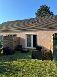 a house with a yard with chairs and a fence at La maison de Charlotte in Auvers-sur-Oise