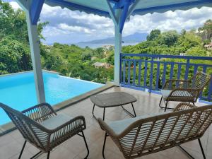 a balcony with chairs and a swimming pool at Les Terrasses de la Wallon Cannelle in Les Trois-Îlets