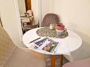 a small white table with a coffee cup and a magazine at Apartman San in Mostar