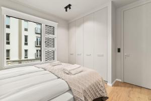 a white bedroom with a bed and a window at City Lux 2BR & 2BA with Free Parking City Center in Reykjavík