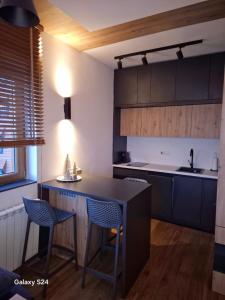 a kitchen with a black counter and chairs in it at Jahorina Apartman Dvosjed B 10 in Jahorina +10 photos