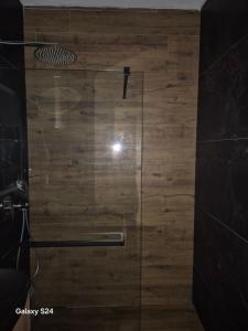 a glass shower door with a wooden wall at Jahorina Apartman Dvosjed B 10 in Jahorina