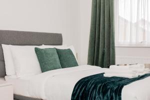 a bedroom with a white bed with green curtains at 2BR with parking, Mill Hill, NW London, 10min Tube in Mill Hill