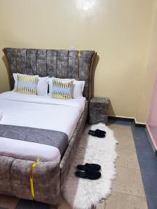a bedroom with a bed with black shoes on a rug at Kipepeo Cozy 1br Skuta-Nyeri in Nyeri