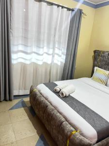 a bed with two rolled towels on it in front of a window at Kipepeo Cozy 1br Skuta-Nyeri in Nyeri +5 photos