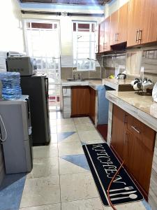 a kitchen with wooden cabinets and a black refrigerator at Kipepeo Cozy 1br Skuta-Nyeri in Nyeri