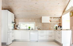 a kitchen with white cabinets and a wooden ceiling at Villa Mormor in Løkken