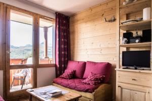 ein Wohnzimmer mit einem roten Sofa und einem TV in der Unterkunft Résidence Le Sextant - SEXTANT 110 MAE-0481 in La Plagne Tarentaise