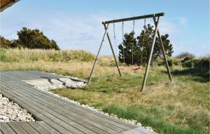 an empty swing set next to a boardwalk at Holiday Home Klitsvinget Ringkøbing Ii in Klegod