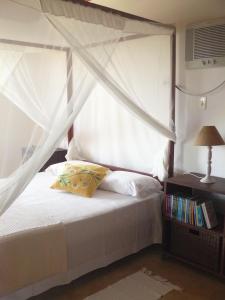 a bedroom with a white bed with a canopy at Pé na Areia in Conde