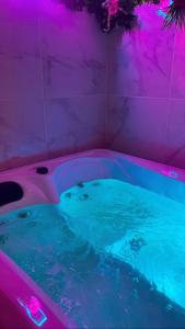 una vasca idromassaggio con illuminazione viola in un bagno di Maison Spacieuse Jacuzzi Wifi Netflix a Quiévrechain