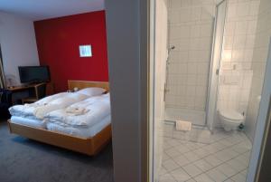 ein Schlafzimmer mit einem Bett und ein Badezimmer mit einer Dusche in der Unterkunft Waldrestaurant & Hotel in Rangsdorf