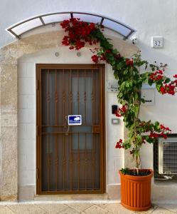 a door to a building with red flowers on it at Adelphòs in Adelfia