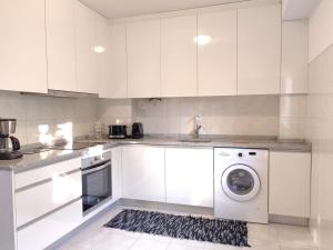a kitchen with white cabinets and a washing machine at esposendebeachapartment in Esposende +2 photos