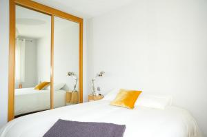 a bedroom with a white bed and a mirror at Apartamentos Madrid Anderson in Madrid