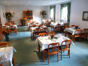 uma sala de jantar com mesas e cadeiras brancas em Hotel Brandenburg em Königs Wusterhausen