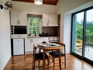 a kitchen with white cabinets and a table and chairs at Refúgio da Montanha in Lajido