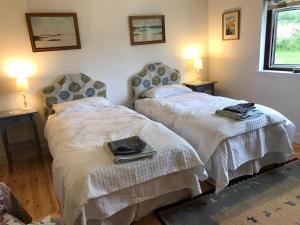 two beds in a room with two lamps on the wall at Rowantree in Kiltarlty