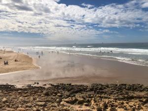 a group of people on a beach with the ocean at Anza surf spot in Agadir
