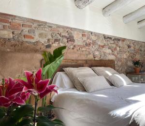 a bedroom with a white bed with a brick wall at Can TABERNER in Bigues i Riells