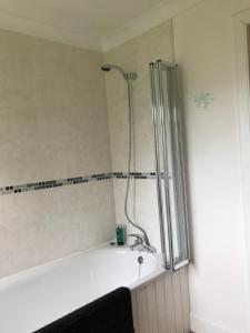 a bathroom with a bath tub with a shower at Rowantree in Kiltarlty