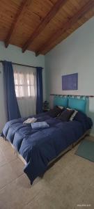 a large bed in a bedroom with blue sheets at La Arcadia in Mina Clavero