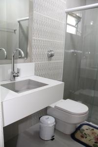 uma casa de banho branca com um lavatório e um WC em Pousada Charme da Serra em Bom Jardim da Serra