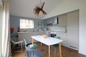 - une cuisine avec une table et des chaises blanches dans l'établissement Woodpecker Lodge - Brook Meadow - sleeps 4 plus 2 - no pets, à Market Harborough