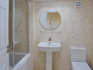 a bathroom with a sink and a toilet and a mirror at Oak Cottage in Winthorpe +2 photos