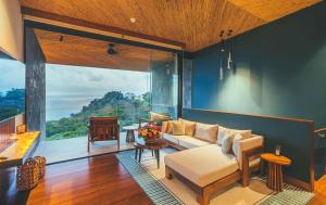 a living room with a couch and a large window at Los Altos Resort in Manuel Antonio