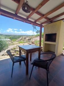 una mesa y 2 sillas en un porche con vistas en Cabañas Agalma, en Villa Yacanto