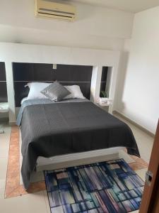 a bedroom with a bed with a black blanket and a rug at Apartamento inn cancun in Cancún